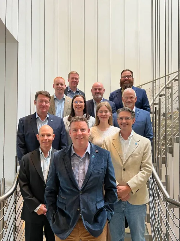 The PTS team standing on stairs in Warsaw with the CEO of the government contracting recruitment company standing in front.